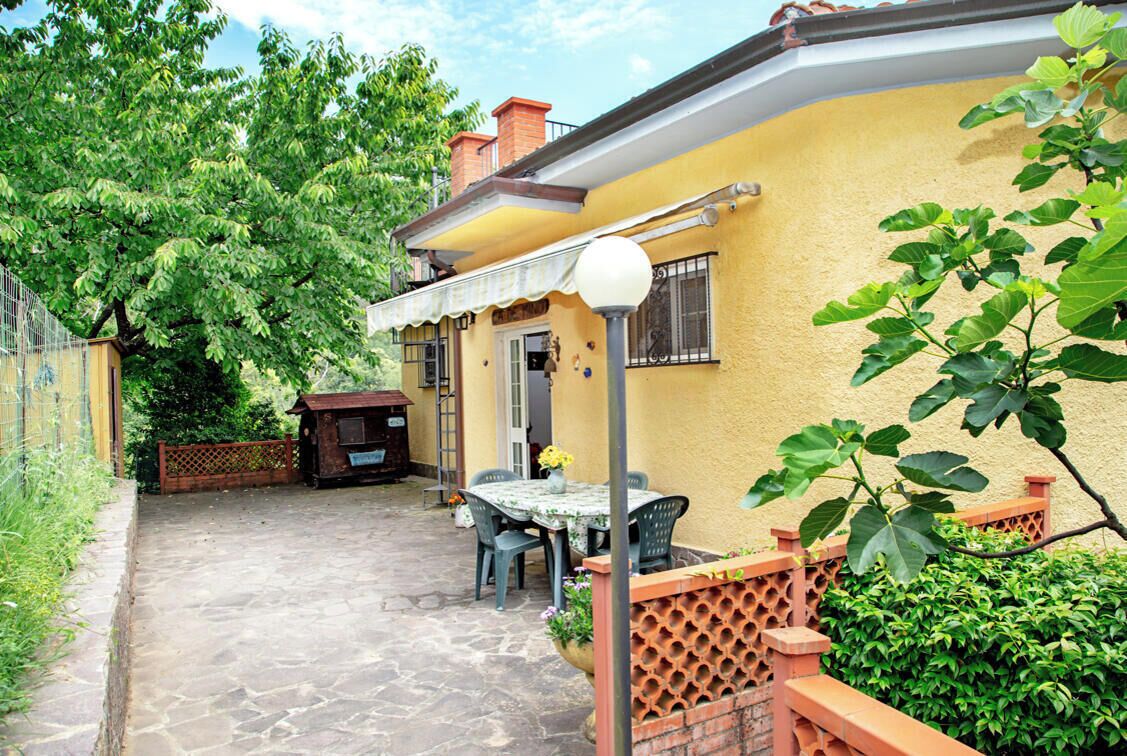 An outdoor patio area with a table and chairs, a lamp post, and a small garden.