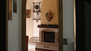 An arched doorway leading to a room with a fireplace, a hanging light fixture, and a patterned wall decoration. - Calice Al Cornoviglio: Cà de Mino (Calice al Cornoviglio)