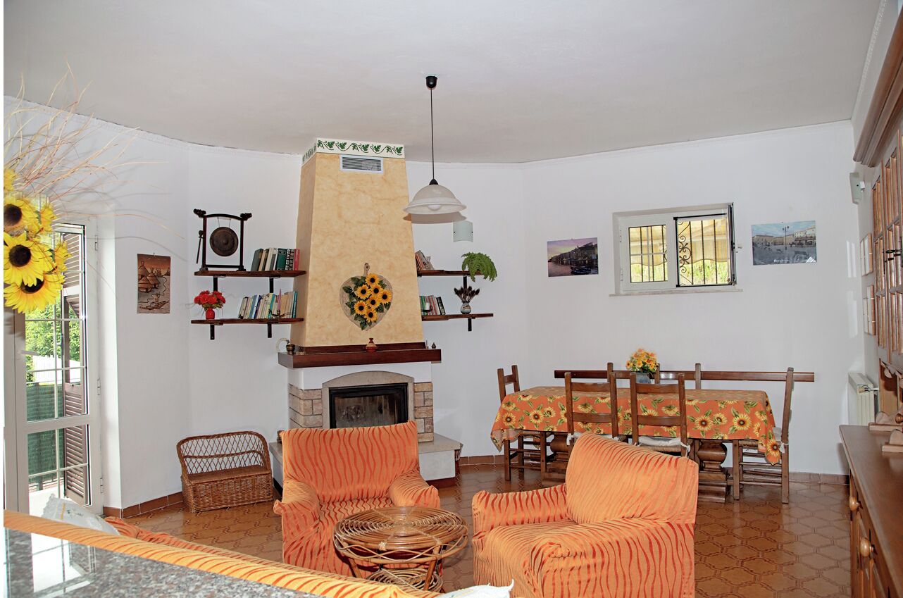 A living room with a fireplace, wicker furniture, and a dining area with a table and chairs.