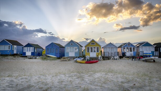 Beach huts with a sandy foreground and a clear sky. - Seaside Cottage with panoramic sea views. (Bournemouth)