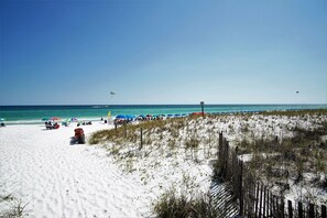 A beach with white sand, a wooden fence, and colorful umbrellas. - Townhouse condo. 3 min walk to private beach.  1 min walk to pool.  (Destin)