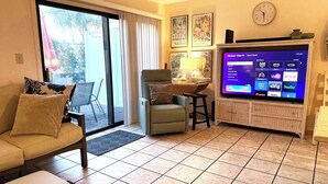 A living room with a sofa, armchair, and a flat-screen TV displaying a guest mode interface. - Townhouse condo. 3 min walk to private beach.  1 min walk to pool.  (Destin)