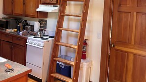 A kitchen with wooden cabinets, a stove, and a wooden ladder. - Cottage-in-the-Barn on Dragonfly Farm (Eastsound)