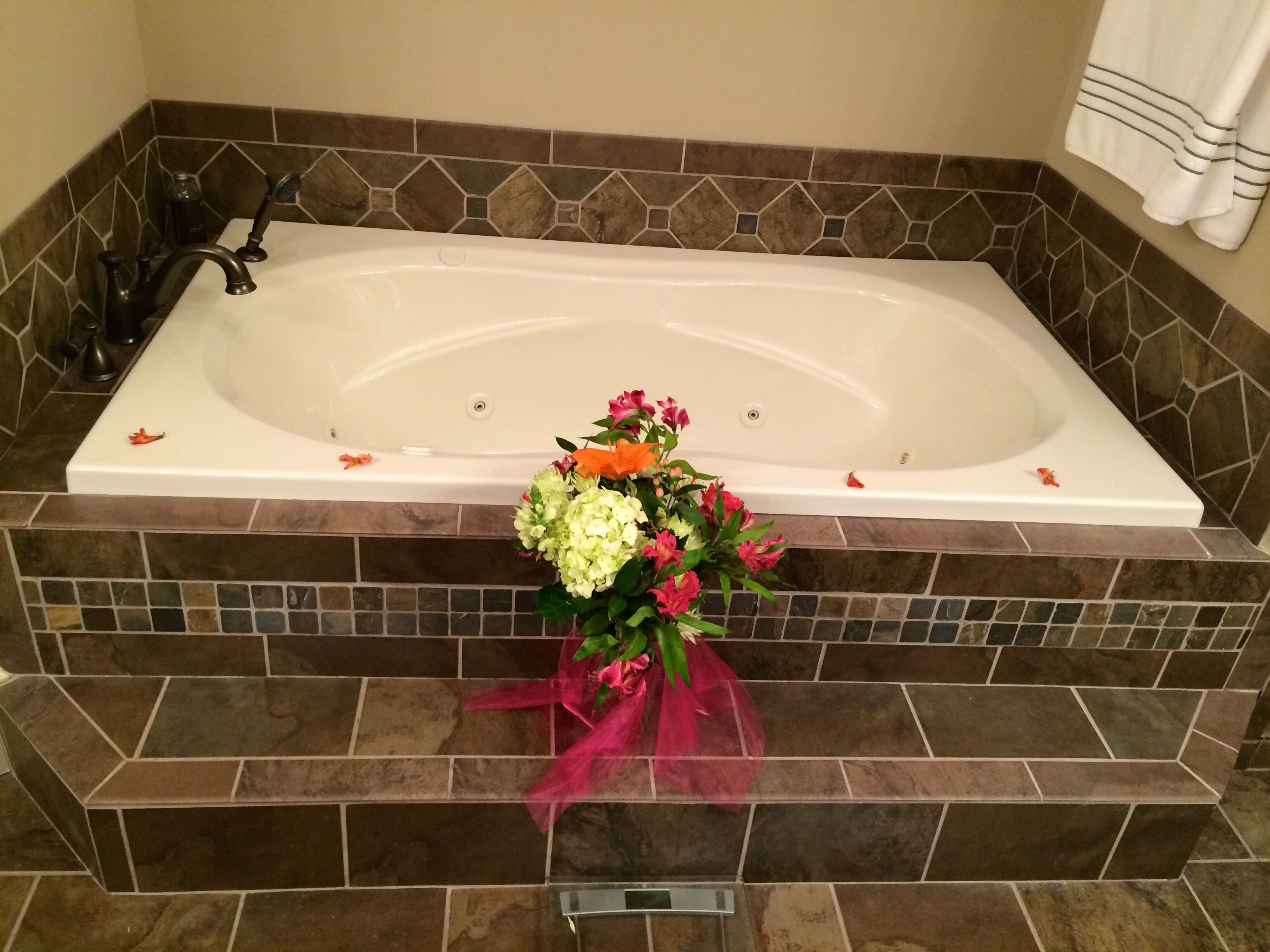 A bathroom with a large bathtub, tiled walls, and a shower area.