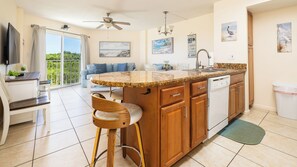 A kitchen with a central island, wooden cabinets, a dishwasher, and a dining area with a table and chairs. - Coastal Comfort in Tavernier - Pool + Beach Access (Tavernier)