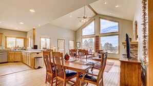 A spacious kitchen with wooden cabinets, a dining table with chairs, and large windows offering views of the outdoors.