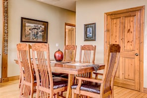 A dining area with a wooden table and chairs, framed pictures on the wall, and a wooden door. - Buffalo Ridge on Zion Boundary very close to the Park! Gated Community -Hot Tub (Mt Carmel)
