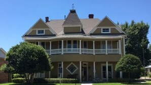 A two-story house with a balcony, a chimney, and a symmetrical facade.