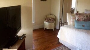 A bedroom with a bed, a chair, a television, and a door.