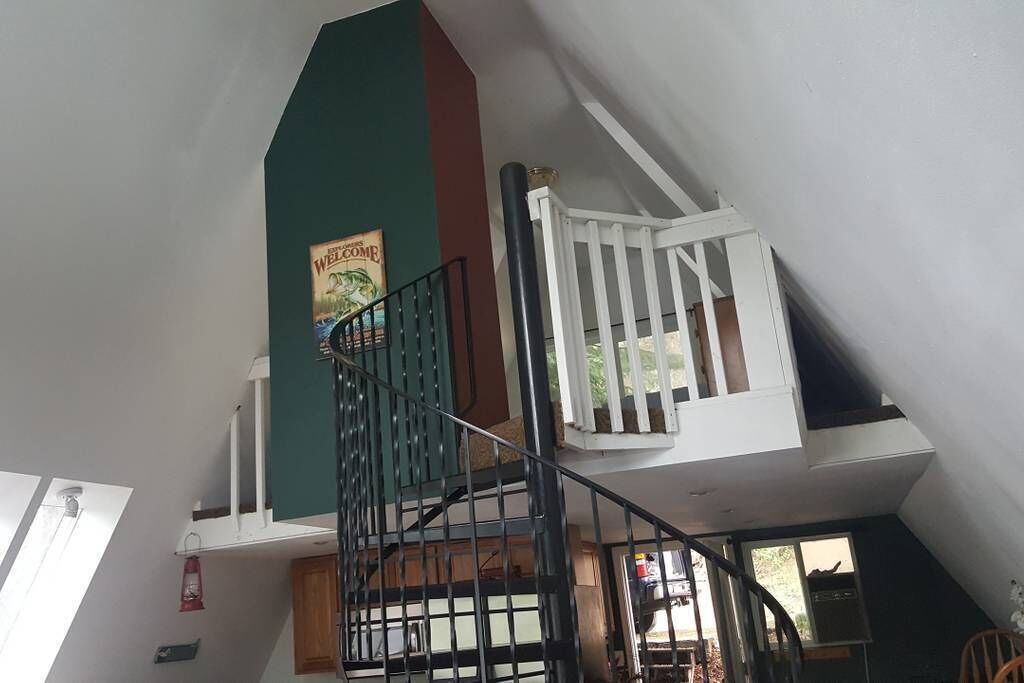 A multi-level interior with a staircase, a green wall, and a poster.