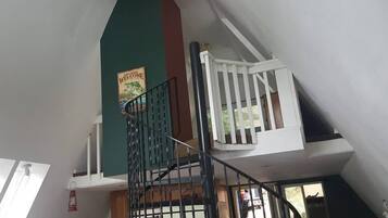 A multi-level interior with a staircase, a green wall, and a poster.