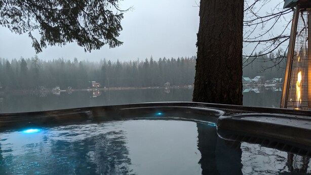 Una piscina interior tranquila con vistas a un paisaje boscoso y un edificio distante.