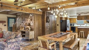 A rustic interior with a wooden dining table, benches, and a floral-patterned sofa.