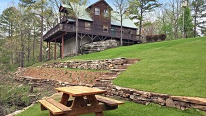A rustic cabin with a stone staircase leading up to a wooden deck.