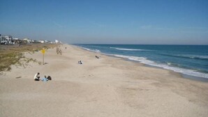 A beach with a clear sky, sandy shore, and a few people relaxing. - Newer home 2 blocks from downtown Carolina Beach (Carolina Beach)