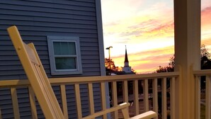 A wooden deck with a green chair and a white chair, overlooking a sunset. - Newer home 2 blocks from downtown Carolina Beach (Carolina Beach)