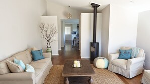 A living room with two sofas, a coffee table, a fireplace, and a hallway leading to a kitchen. - Charm and Modern Luxury in Heart of Wine Country (Sonoma)