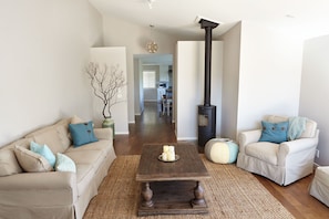 A living room with two sofas, a coffee table, a fireplace, and a hallway leading to a kitchen.