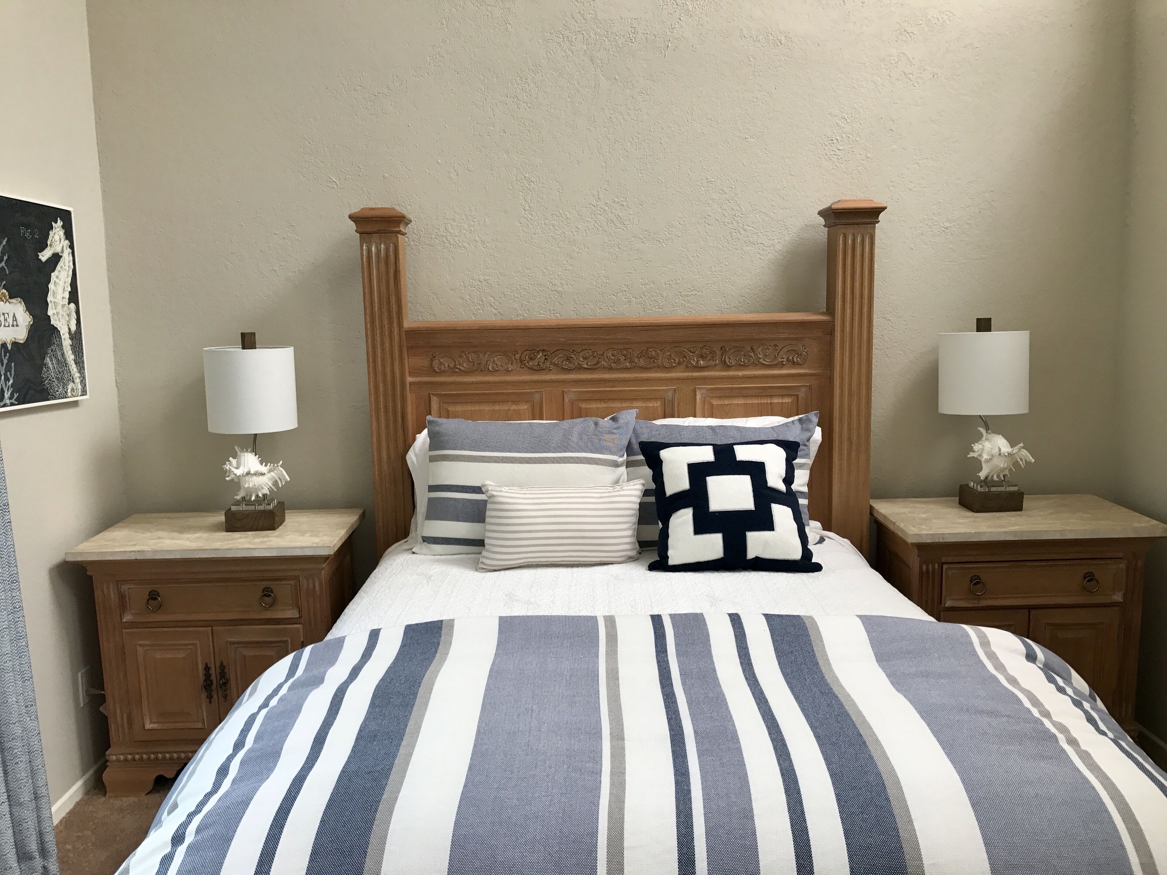 A bed with a striped bedspread, two nightstands with lamps, and a headboard with vertical panels.
