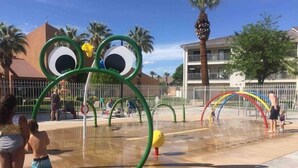 Parque acuático con una estructura de juego con forma de rana y un tobogán de agua arcoíris.