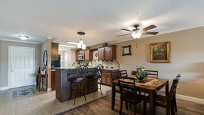 A spacious kitchen with wooden cabinets, a central island, and a dining area with a table and chairs.