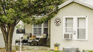 Ein Haus mit Veranda, einer Uhr und einem kleinen Garten.