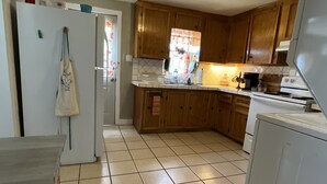 Eine Küche mit Holzschränken, einem weißen Kühlschrank und einem gefliesten Boden.