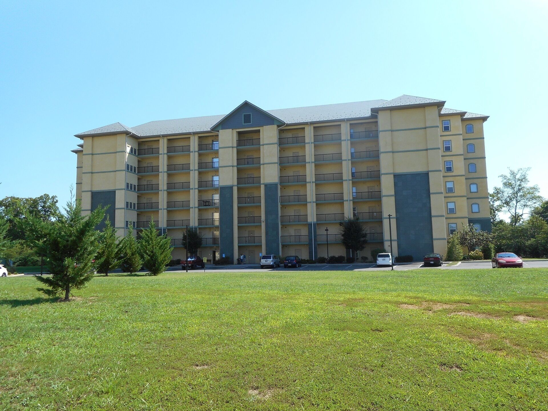 A multi-story hotel with a central courtyard, balconies, and a parking area.