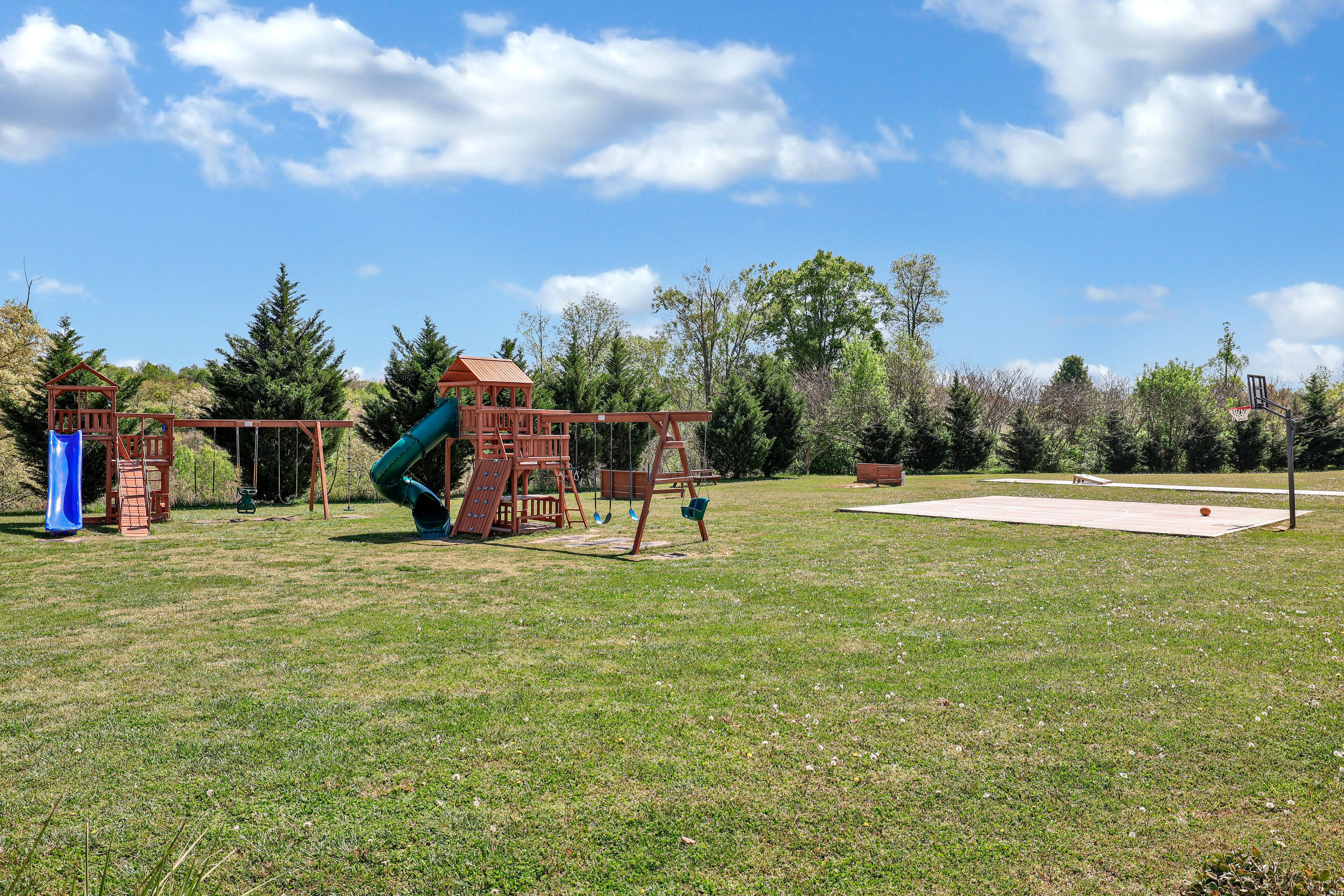 A playground with a slide, swings, and a basketball court.