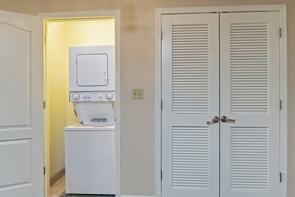 A laundry room with a washing machine and dryer, a door with a lock, and a light switch on the wall.