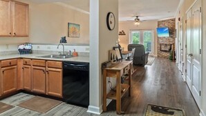 A kitchen with wooden cabinets, a dishwasher, and a dining area with a table and chairs. - STAY NEAR THE STRIP, ONE MINUTE OFF PARKWAY WITH SENSATIONAL VIEWS. (pigeon forge)