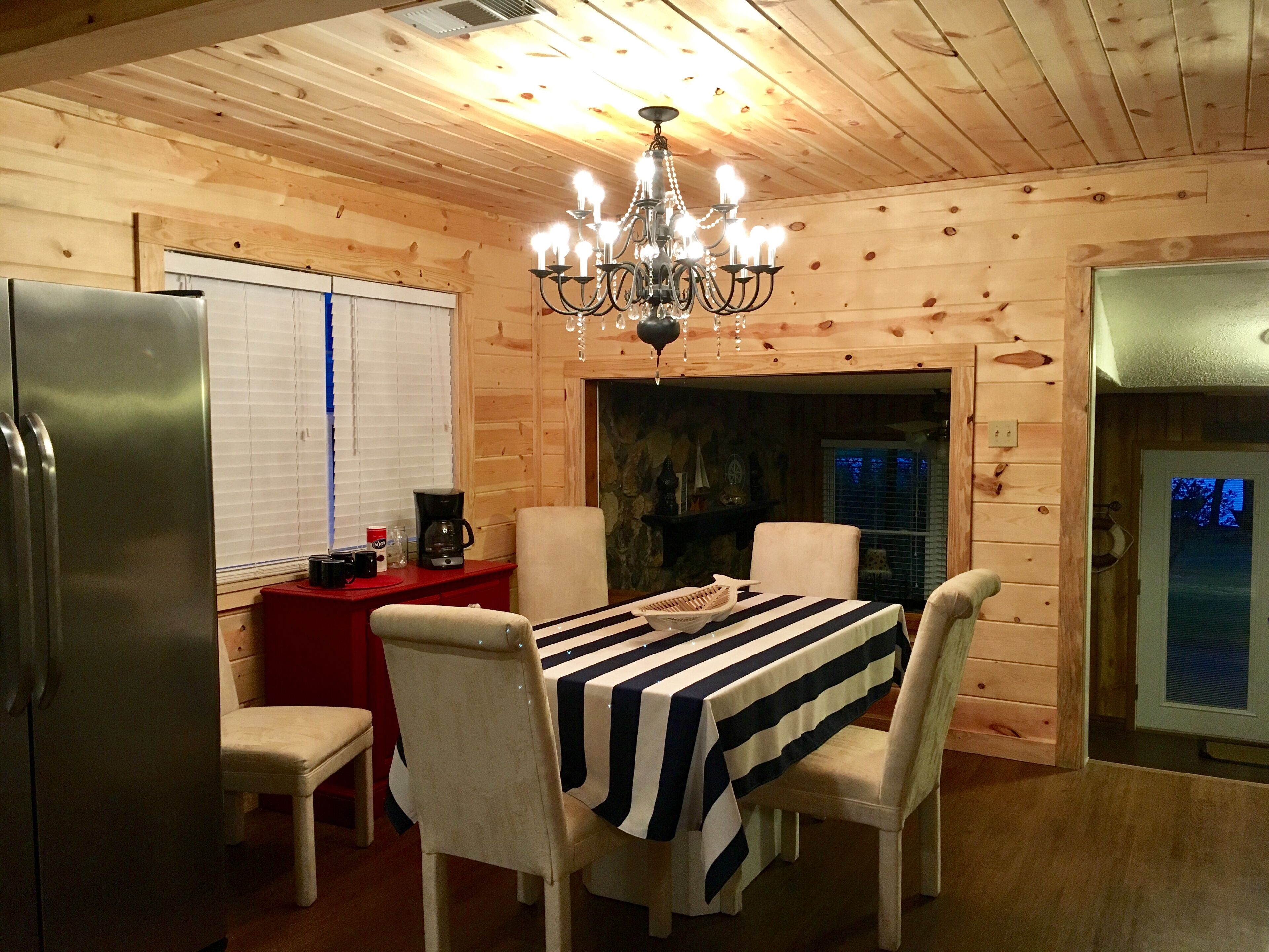 L’intérieur d’un chalet en bois chaleureux et accueillant, avec une table à manger dressée pour quatre personnes, un lustre et une cheminée en pierre.