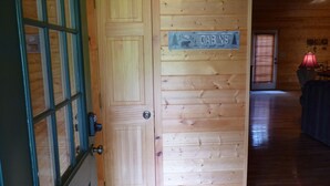 Eine Holztür mit einem Schild, auf dem 'CABINS' steht, und ein Fenster mit Jalousien.
