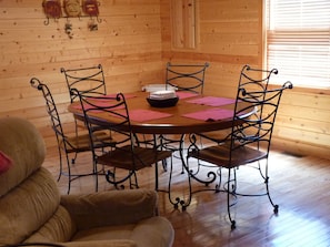 A wooden interior with a round table, four chairs, and a sofa.