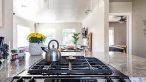 A modern kitchen with a gas stove, kettle, and various kitchen items. - Charming Mid-Century Craftsman ~ Hot Tub/Serene Yd (San Diego)