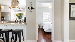 A modern kitchen with a central island, bar stools, and a visible stove. - Charming Mid-Century Craftsman ~ Hot Tub/Serene Yd (San Diego)