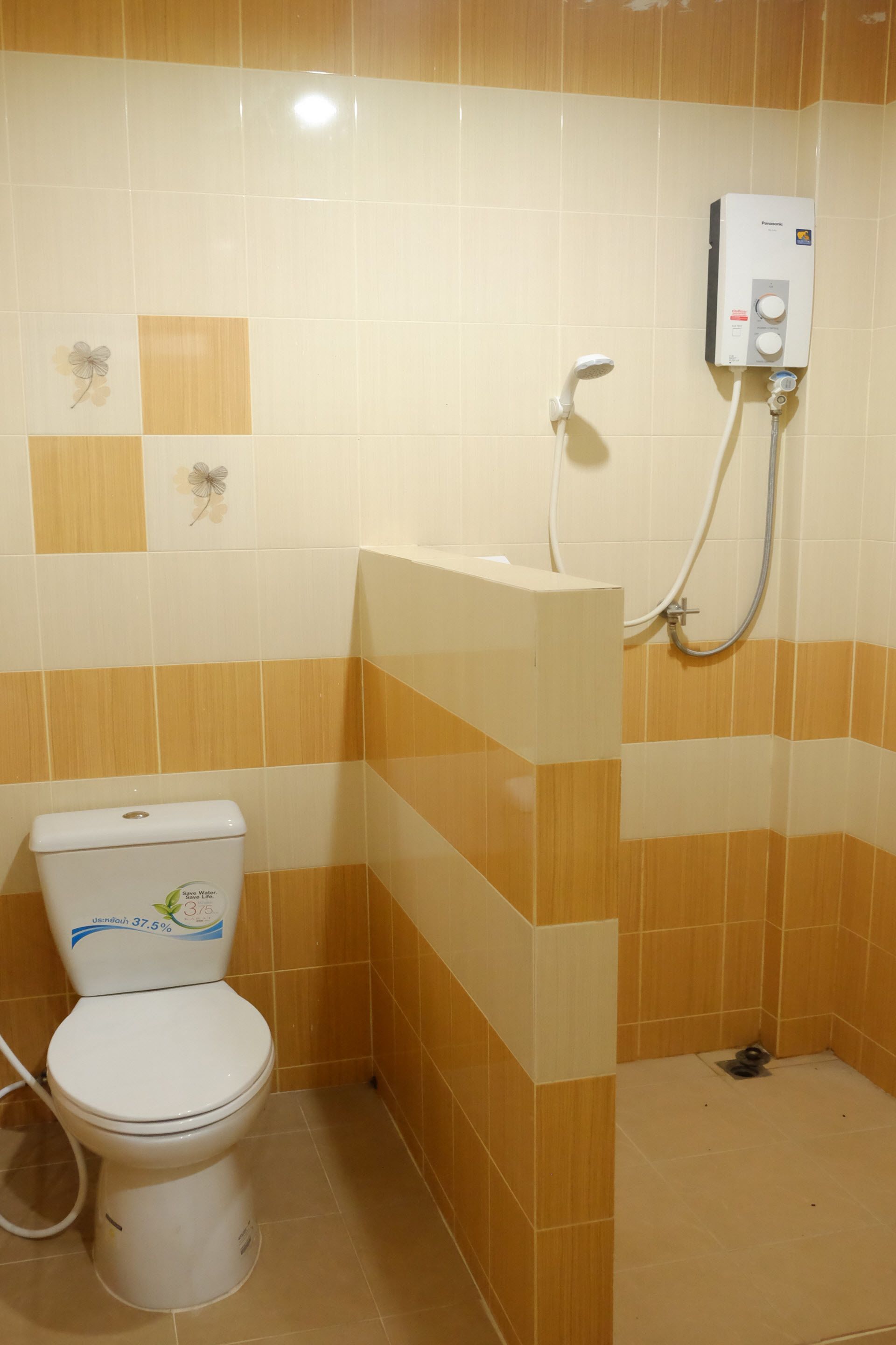 Uma casa de banho com sanita, chuveiro e termoacumulador.