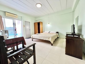A bedroom with a bed, a wooden wardrobe, a desk with a computer, and a window with curtains. - Sunshine Place Udon (Udon Thani)