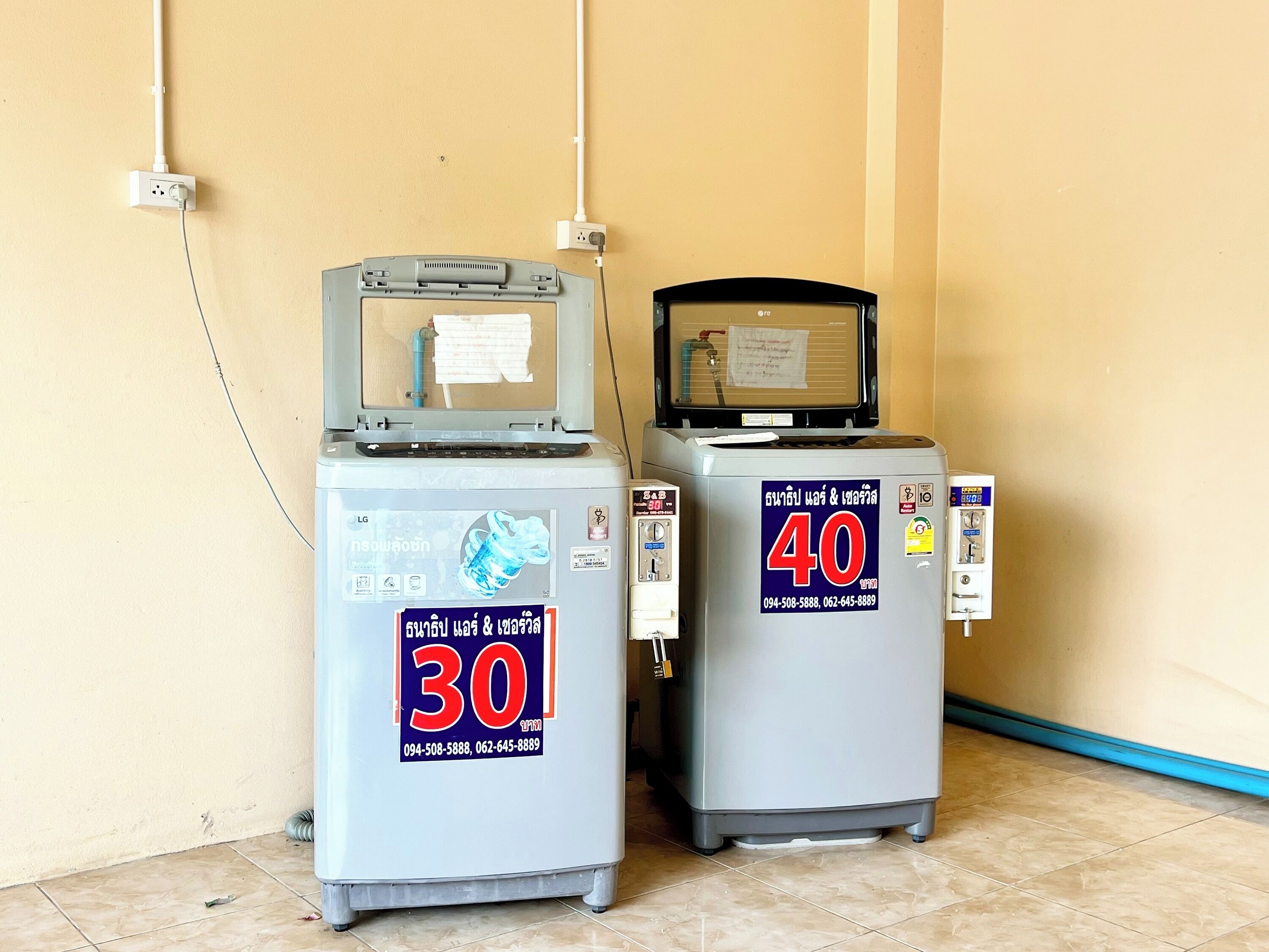 Dos dispensadores de agua, uno etiquetado con el número 30 y el otro con el número 40, frente a una pared beige con suelo de baldosas.