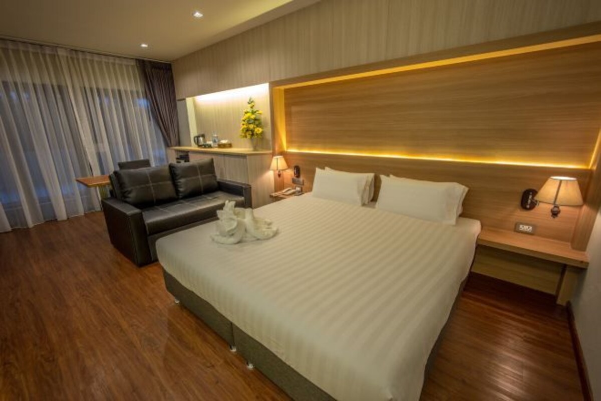 Una habitación de hotel moderna con una cama grande, un sofá, un escritorio y un espejo.