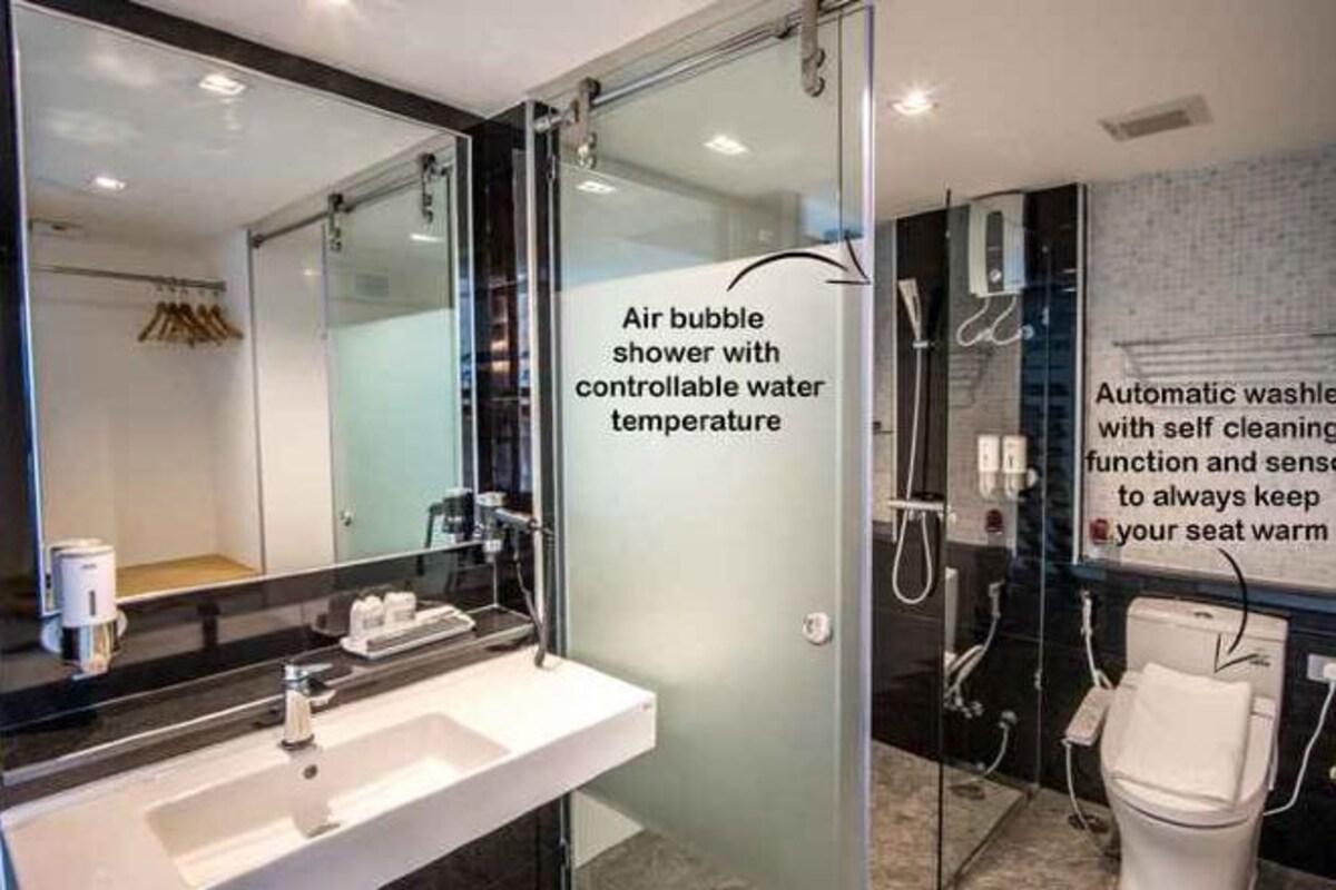 Un baño moderno con cabina de ducha de vidrio, lavamanos con espejo y un inodoro automático con función de autolimpieza.