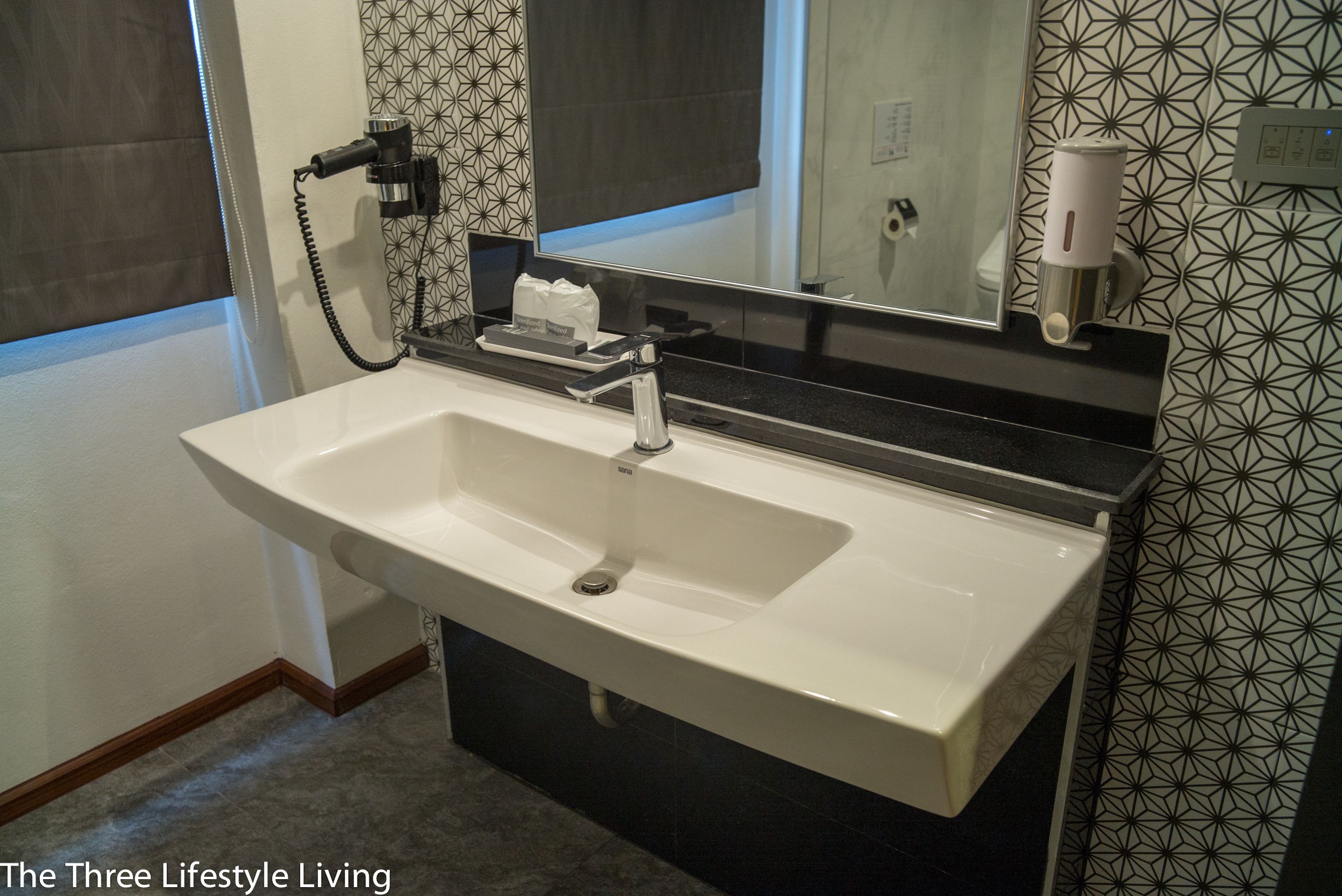 A bathroom with a white sink, a mirror, and a towel dispenser.