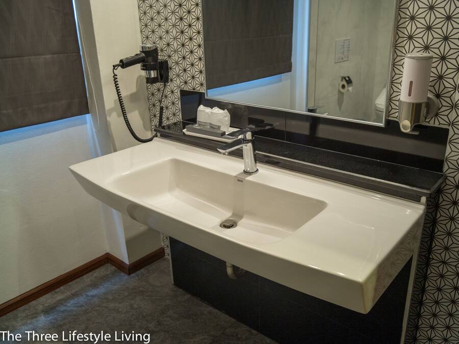 A bathroom with a white sink, a mirror, and a towel dispenser.