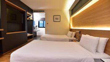 A hotel room with two beds, a wooden headboard, a bedside table, and a wall-mounted TV.