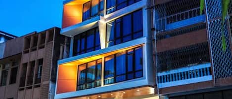 Un hotel de varios pisos con balcones, un restaurante en la planta baja y un letrero en un idioma extranjero.