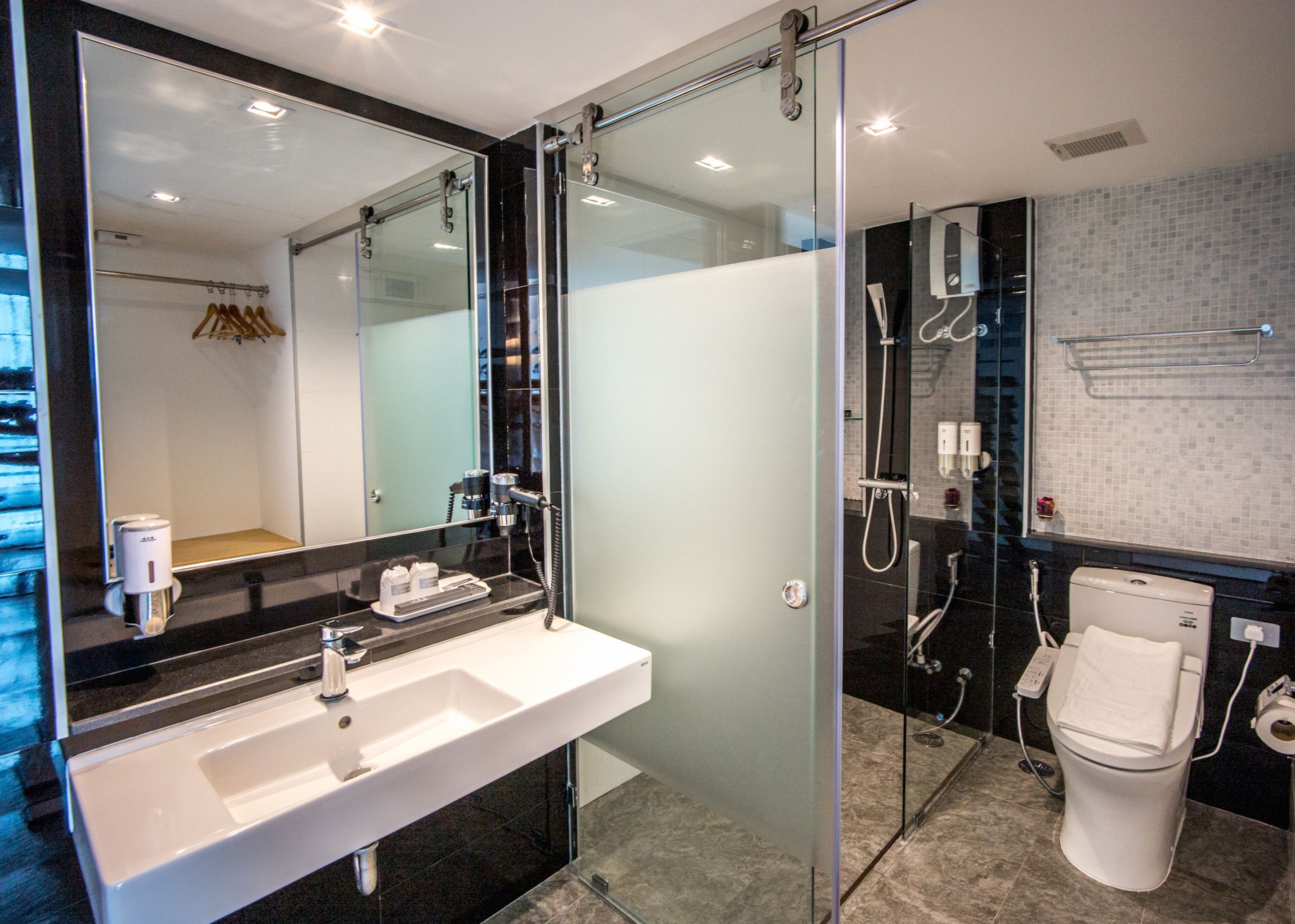 A modern bathroom with a glass-enclosed shower, a white sink, and a toilet.