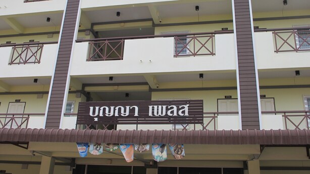 A multi-story building with balconies and a sign that reads "U1 U.N. WAA". - Boonya Place (Chonburi)