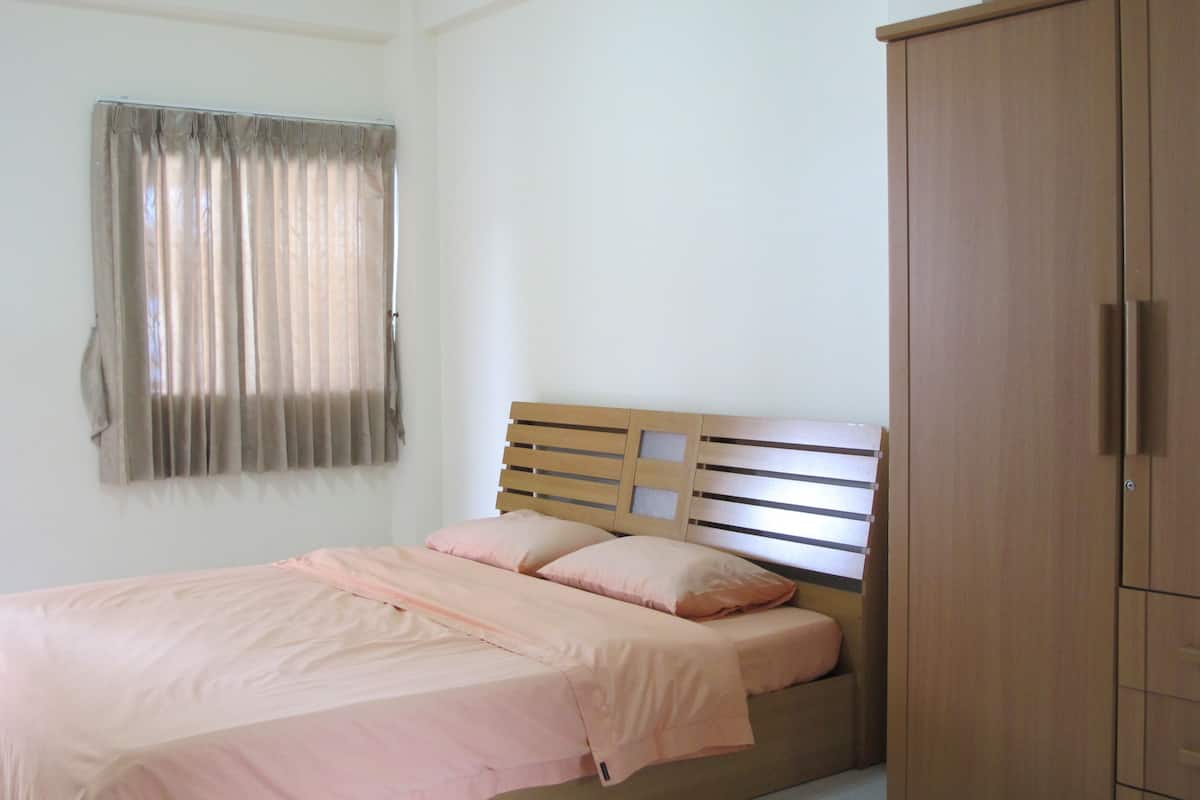 Un dormitorio con una cama, un armario y una ventana con cortinas.