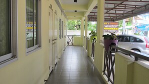 A corridor with doors, a tiled floor, and a balcony with a railing. - Boonya Place (Chonburi)