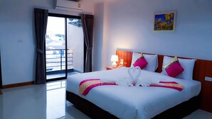 A hotel room with a large bed, a nightstand, a lamp, a painting on the wall, and a sliding door to the balcony. - The Terrace Khlongtoei (Hat Yai)